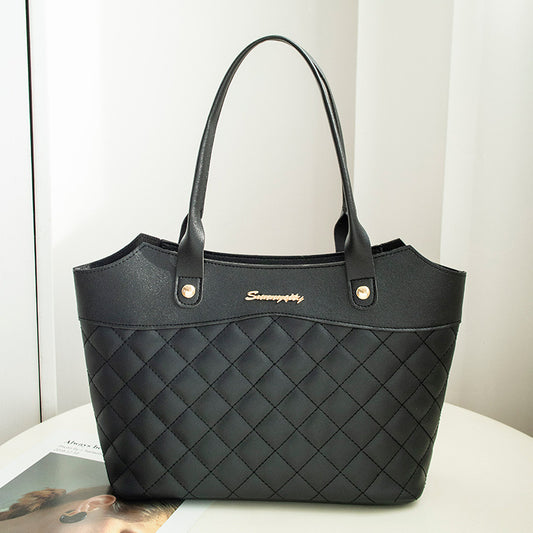 Black quilted handbag with gold logo on a white surface